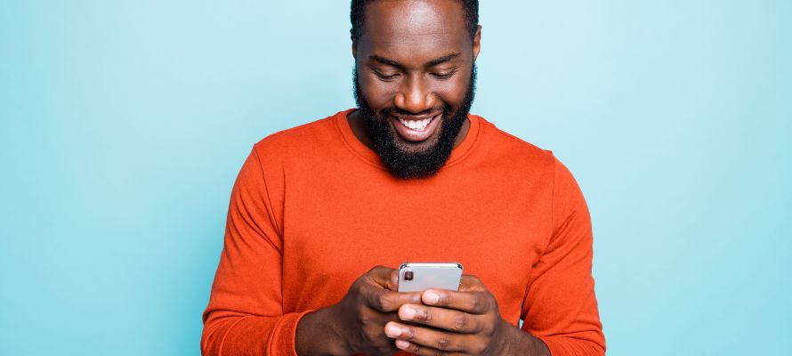 man using his iPhone and smiling